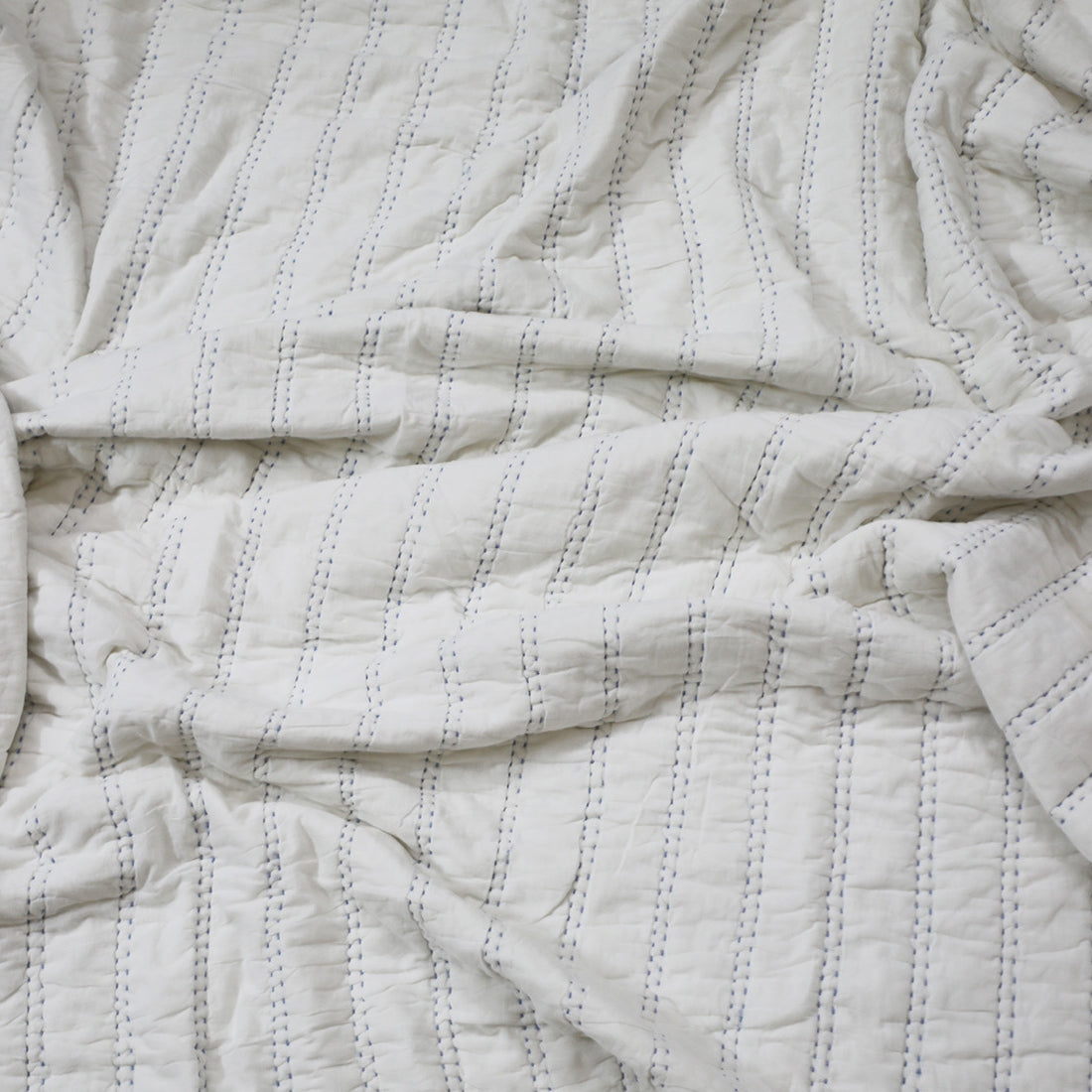 white organic hand quilted quilt styled on bed
