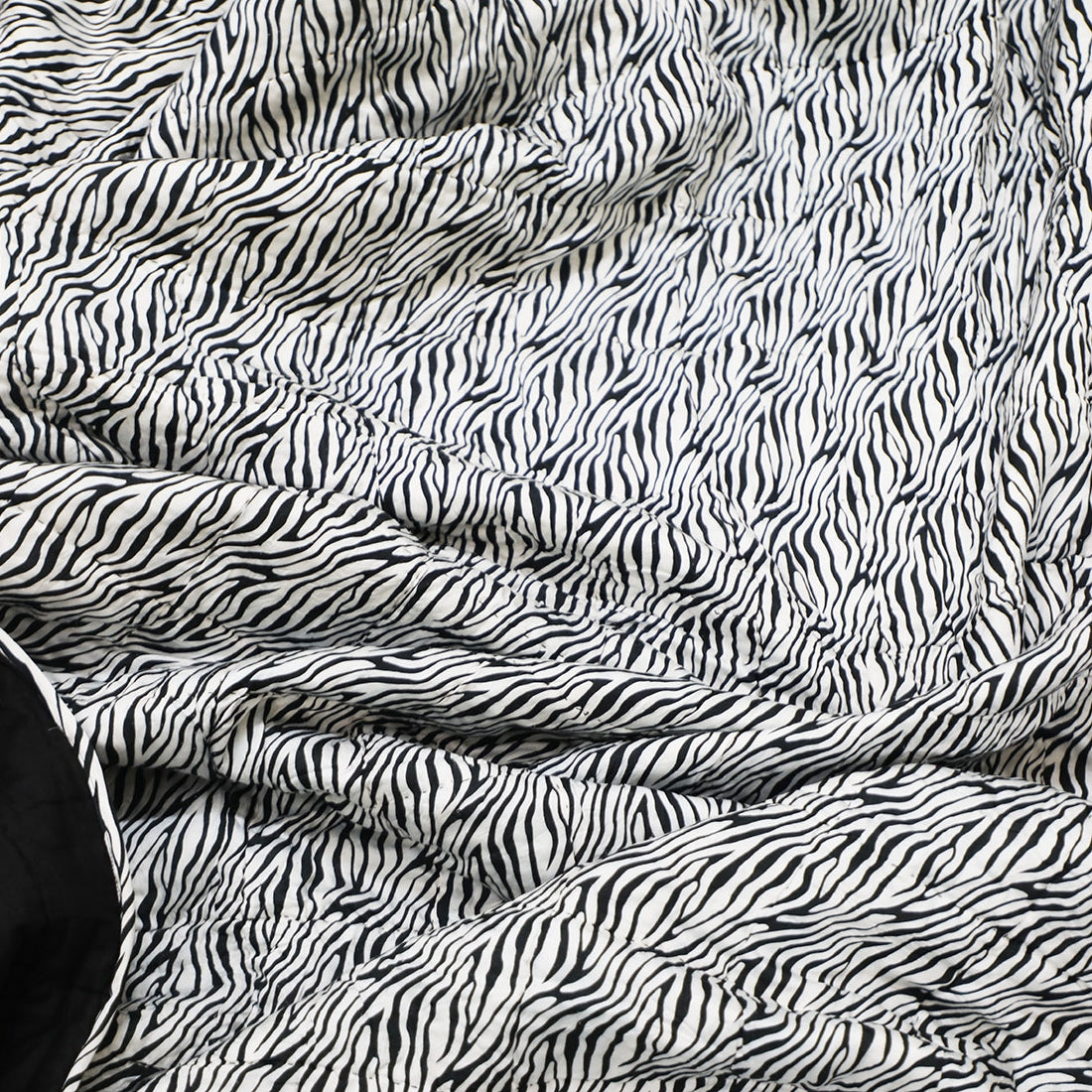 black & white printed cotton quilt styled on bed
