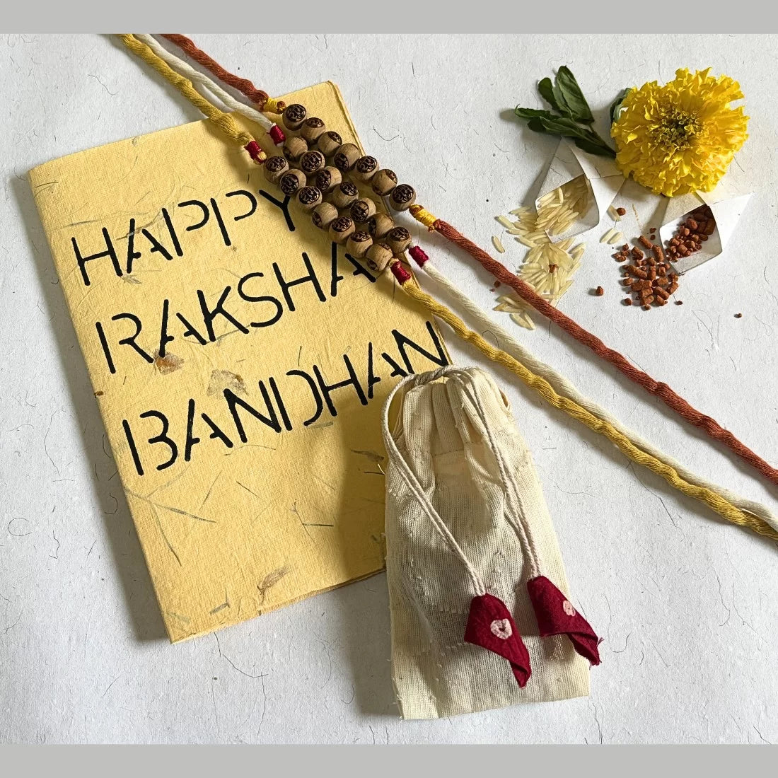 Eco-friendly Tulsi bead rakhi with Ram carving. Natural dyed organic cotton threads in Red and White and Yellow. Handmade by women artisans. Comes in cotton potli.