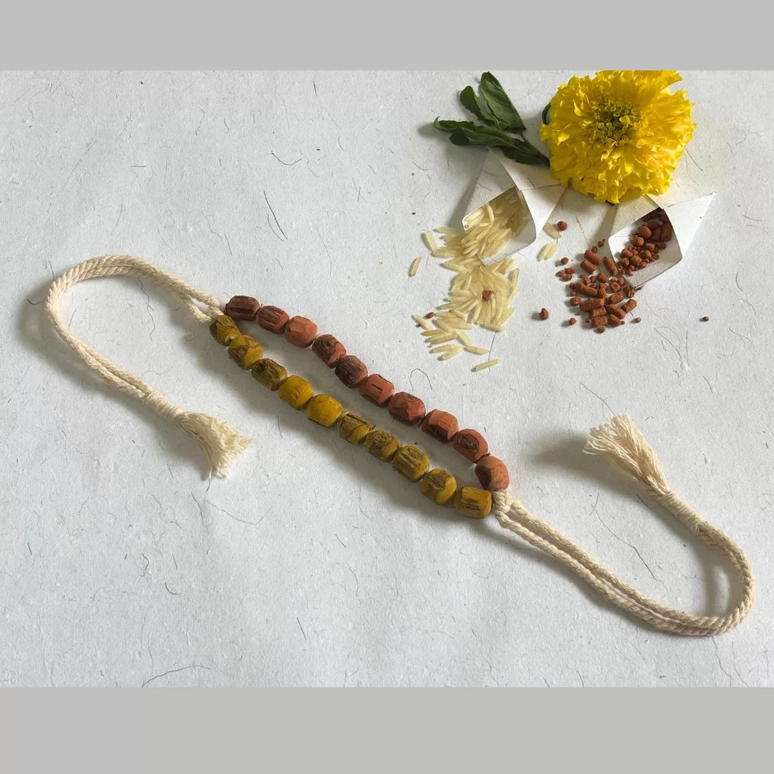 Eco-friendly Tulsi bead rakhi naturally dyed in Madder Red and Turmeric Yellow. 15-17 inches. Comes in cotton potli with recycled card. Handmade in India.
